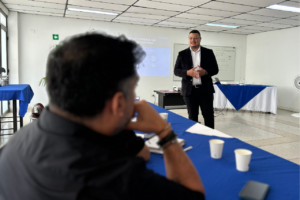 Persona exponiendo frente a un grupo en una sala de reuniones, explicando el uso de inteligencia artificial conversacional para el desarrollo digital empresarial. Russell Bedford.