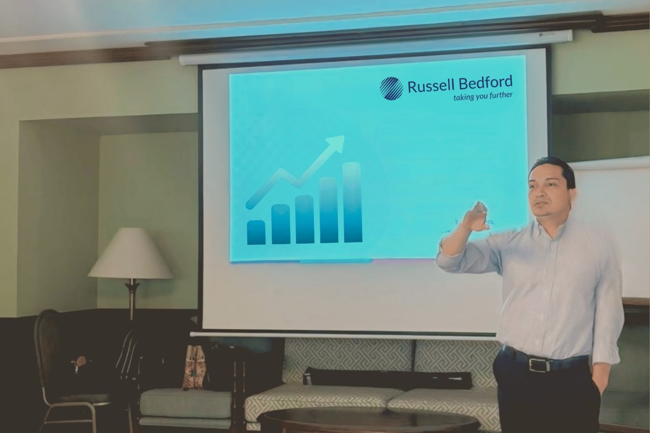 Expositor de Russell Bedford que presenta gráfico de crecimiento sobre indicadores financieros en una sesión empresarial.
