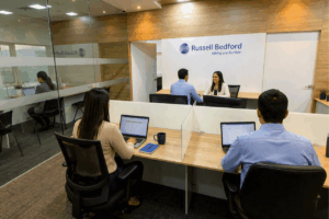 Oficinas de Russell Bedford Colombia con profesionales trabajando y atendiendo a un cliente en un entorno corporativo.
